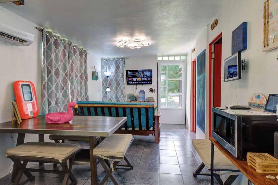 Bright, AC-cooled living/dining with smart TV, bench seating, coastal vibe.