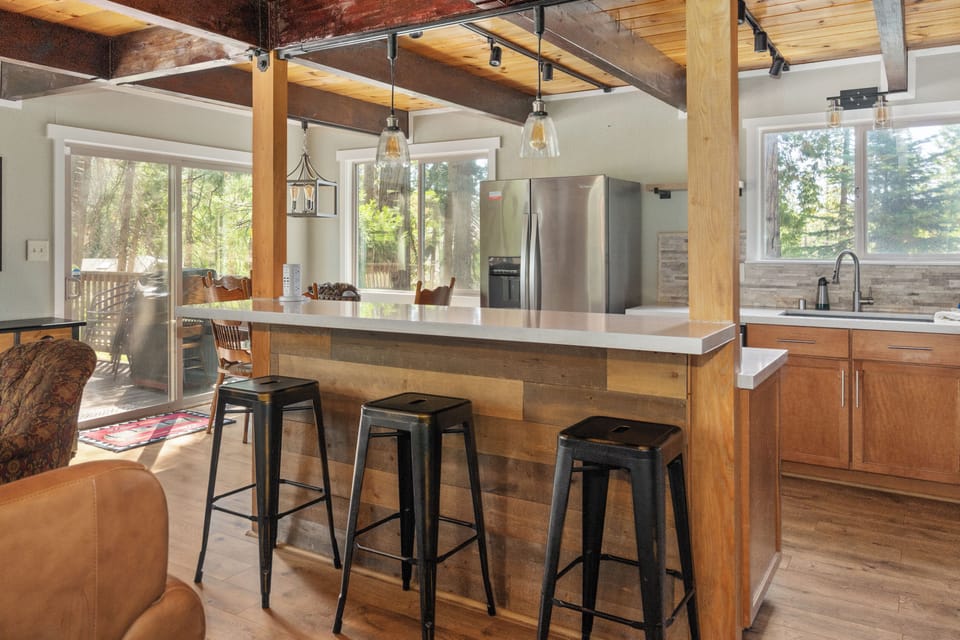 Gather around the spacious kitchen island, bathed in natural light from floor-to-ceiling windows overlooking the trees. Rustic wood beams and modern finishes create your perfect mountain retreat cooking space.