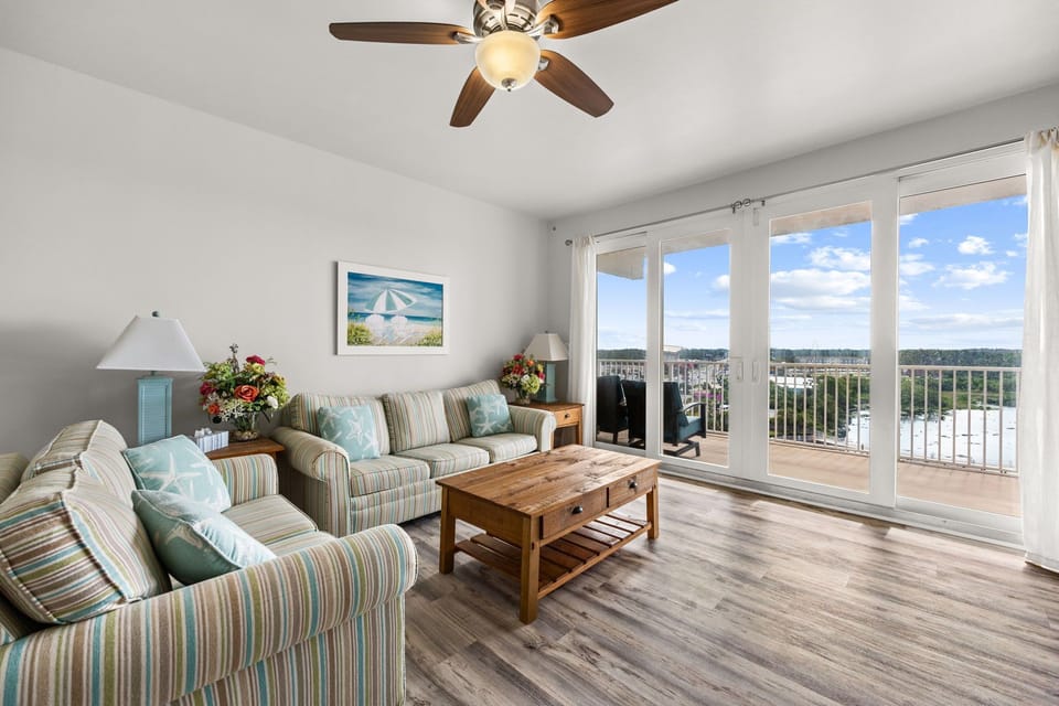 Relax in your bright living room with spacious seating, coastal accents, and sliding doors that open to your private balcony overlooking scenic waterfront views.