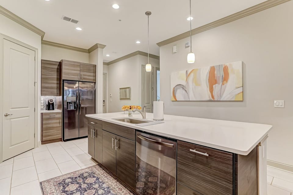 Your modern kitchen features sleek stainless appliances, expansive white countertops, and warm wood cabinetry—a perfect space to prepare meals and gather with loved ones in style.