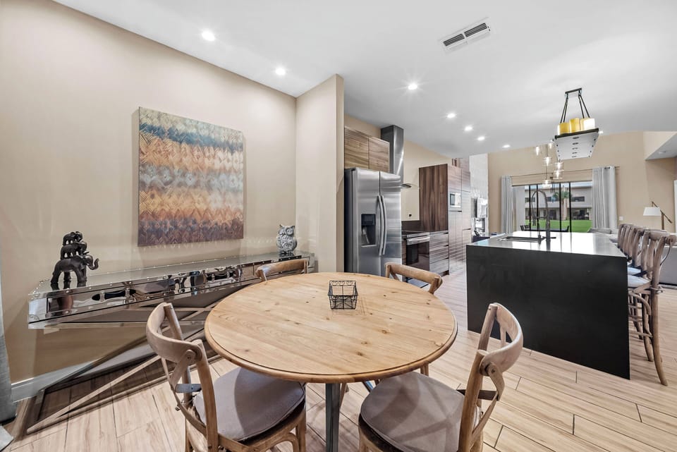 Enjoy a stylish dining area that blends comfort and sophistication, featuring a rustic wooden table with elegant chairs. The warm art and sleek kitchen create a welcoming atmosphere, perfect for gathering with friends and family.