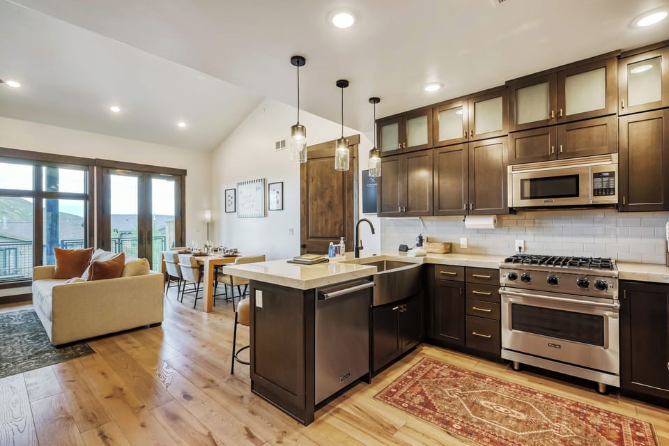 Step into your open-concept retreat with a fully-equipped gourmet kitchen, elegant wood cabinetry, and a spacious island perfect for morning coffee or meal prep.