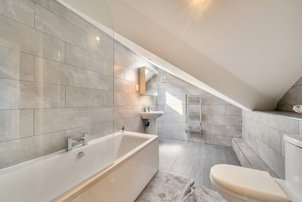 Second stylish bathroom with contemporary tiling, bath and sunlit finish.
