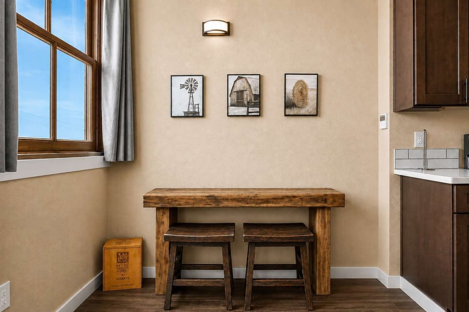 🍽️ Enjoy casual meals or morning coffee at this charming dining nook, featuring a rustic wood table and two stools.