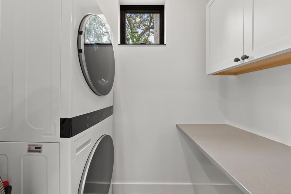 [Laundry room - Main Floor | Stacked washer/dryer and folding space]