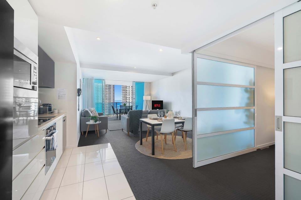 Enjoy bright and seamless open-plan living in this modern apartment, featuring a fully equipped kitchen, a stylish dining setup, frosted glass sliding doors, and a light-filled lounge leading out to a private balcony with scenic views.