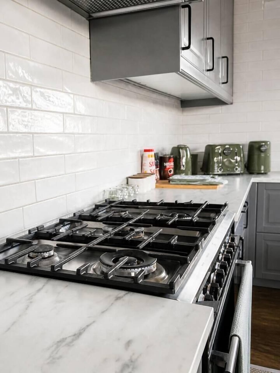 5-burner gas cooktop with rangehood and stone benchtops — fully equipped to cook for the whole group, with quality cookware provided.