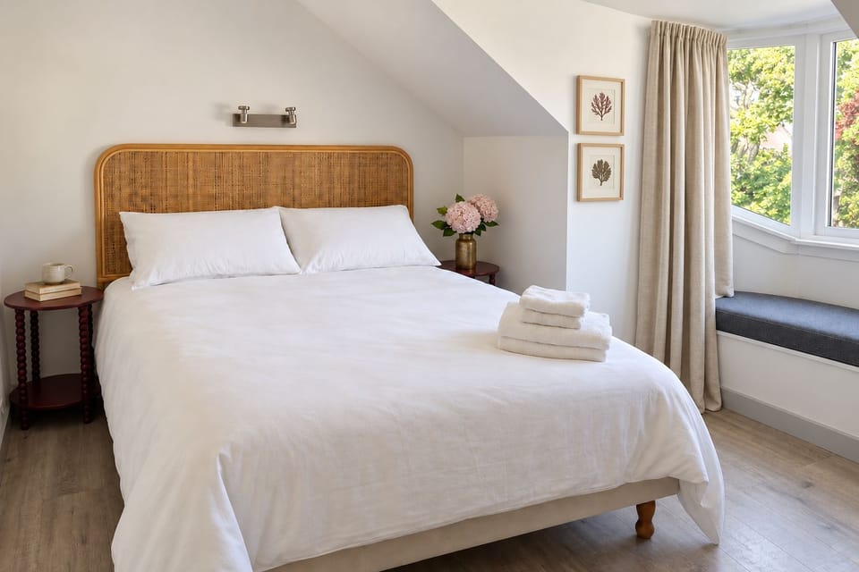 Bright cozy bedroom with bay window seat and crisp white linens