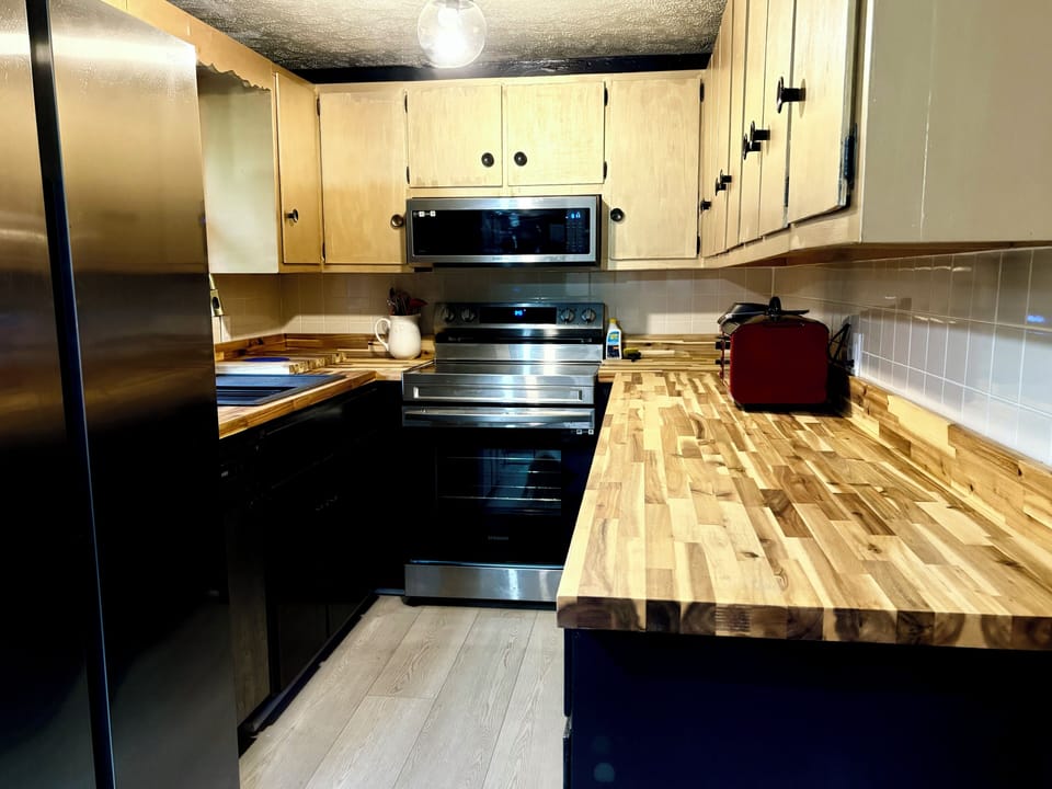 Kitchen with butcher block counters and smart stainless appliances.