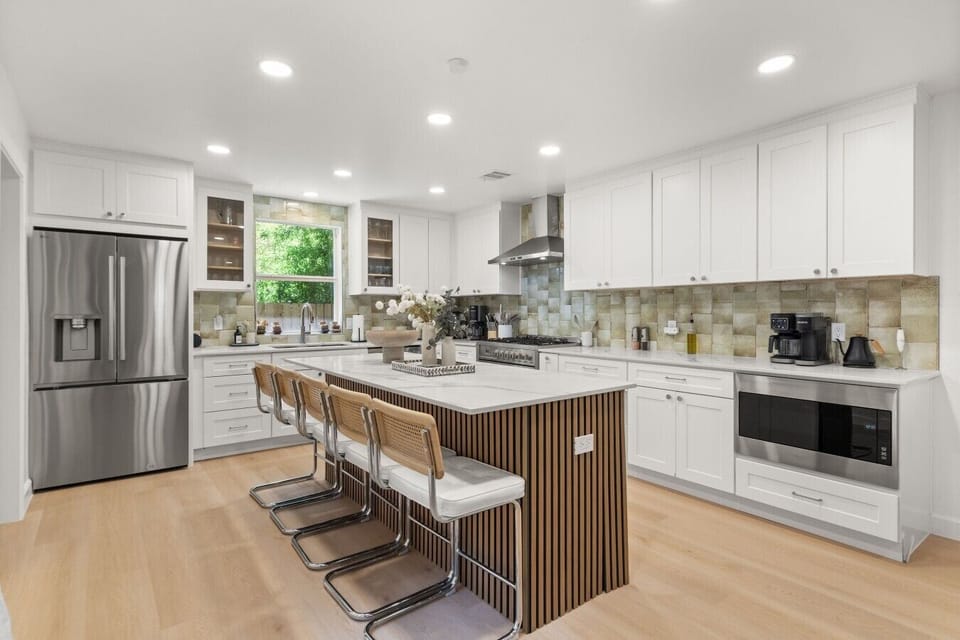 Cook and gather around the marble island in this fully stocked kitchen, complete with a gas range and rattan bar seating.