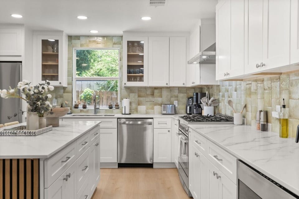 Prep meals with ease in this bright kitchen featuring marble counters, stainless appliances, and a garden view over the sink.