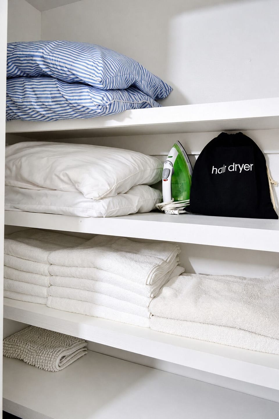 Well-stocked linen closet with fresh towels, extra bedding, iron & hair dryer