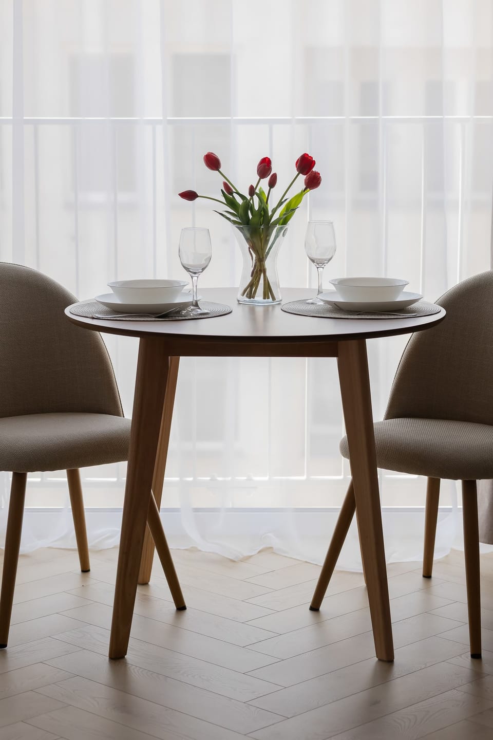 A small dining area with a round table and two chairs decorated with fresh flowers.