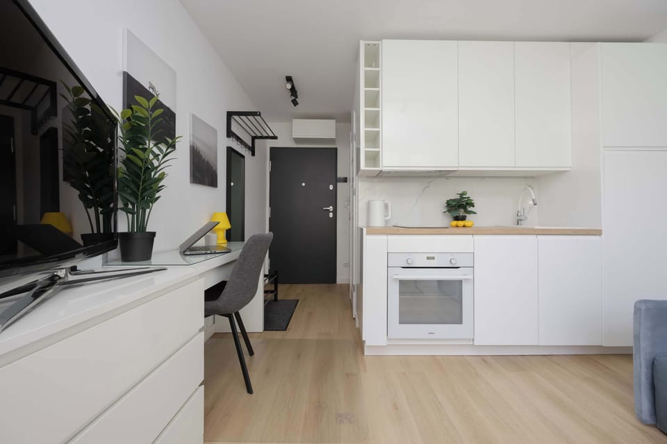 Modern kitchenette with white cabinetry, built-in appliances, a refrigerator, and practical storage space.