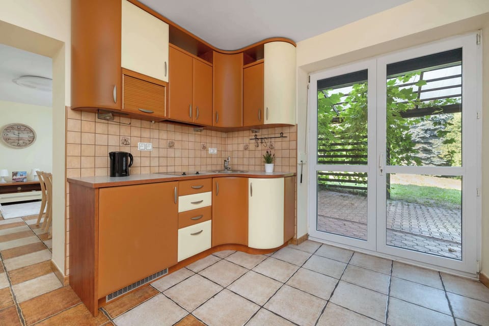 Functional kitchenette with wooden cabinets, tiled floor, and a large window.