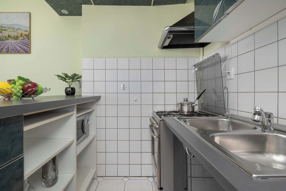 Modern kitchen with a sink, cabinets, kettle, and cooking area.