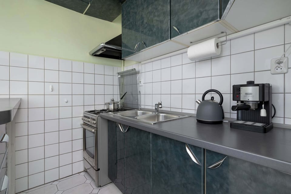Functional kitchen with dark countertops, white tiled walls, and appliances.