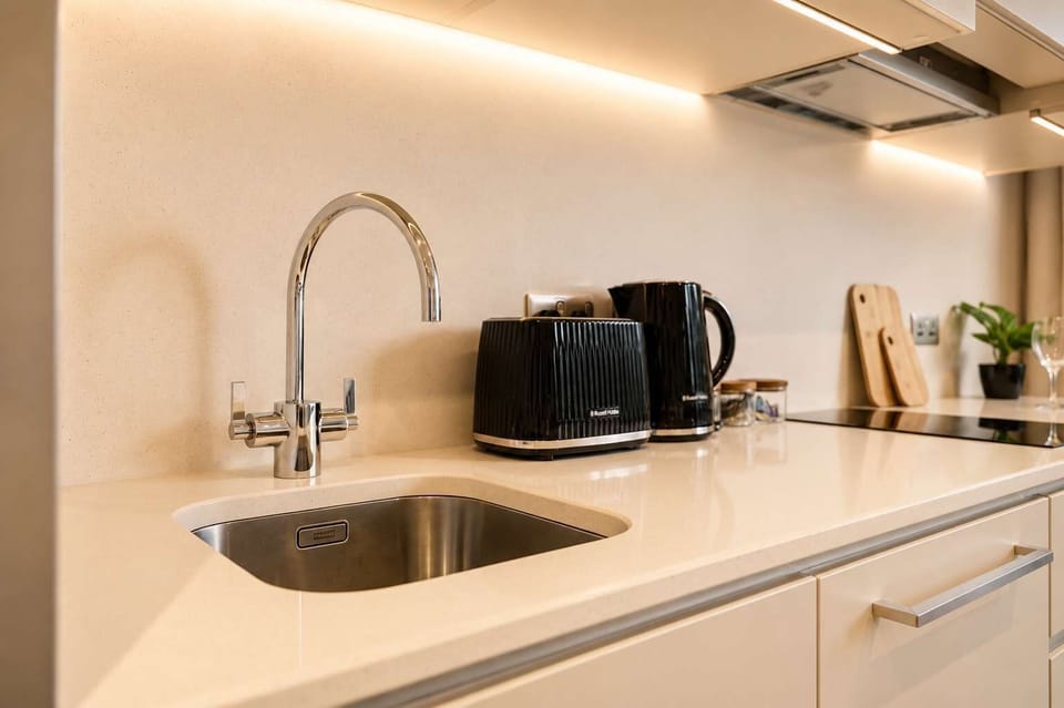 The modern kitchen features sleek finishes and is equipped with an oven, hob, fridge/freezer, cookware, crockery, and utensils, providing everything needed to prepare convenient meals during both short visits and extended stays.