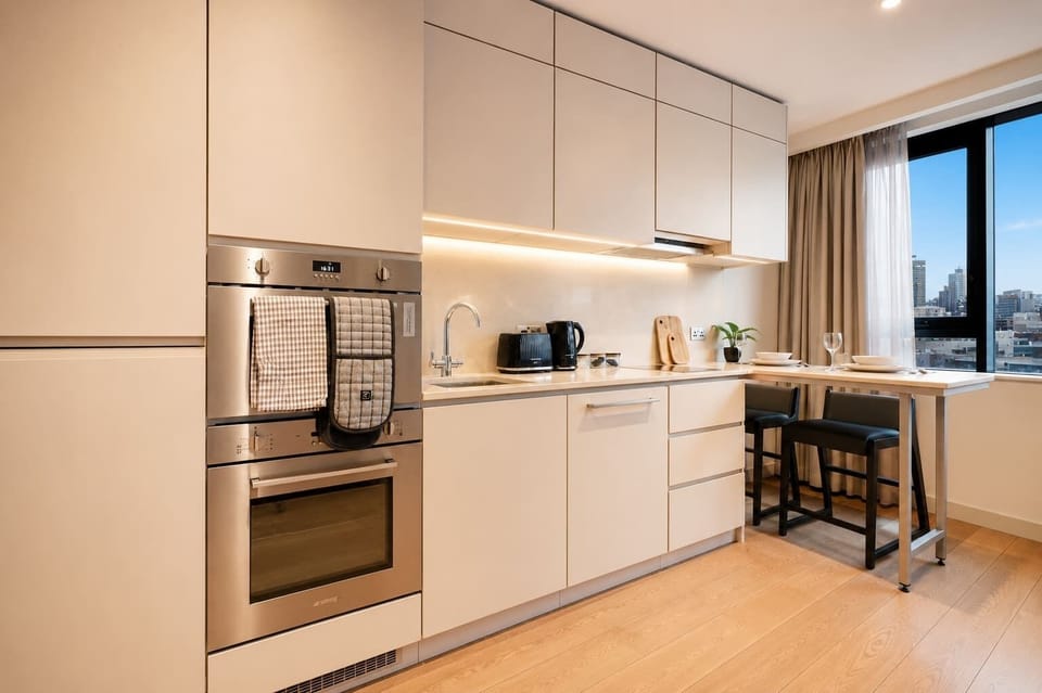 A stylish modern kitchen with sleek finishes provides a practical space for meal preparation. It includes an oven, hob, fridge/freezer, cookware, crockery, and utensils, making it well-suited to both short and longer stays.