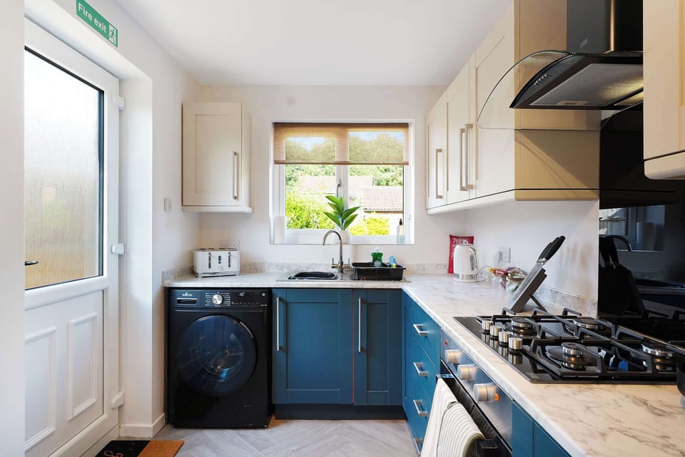 Bright and functional kitchen featuring essential appliances, cooking facilities, practical storage and a washing machine, making meal preparation and everyday living effortless.