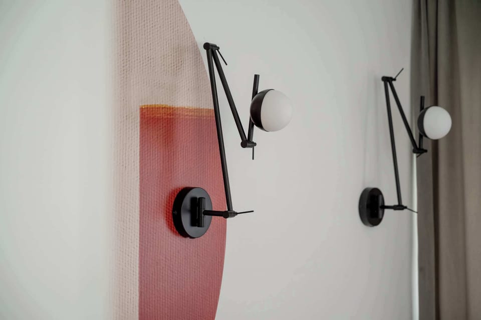 A close-up of modern black reading lamps mounted against a white wall with subtle painted accents. Their sleek adjustable arms blend functional design with decorative style.