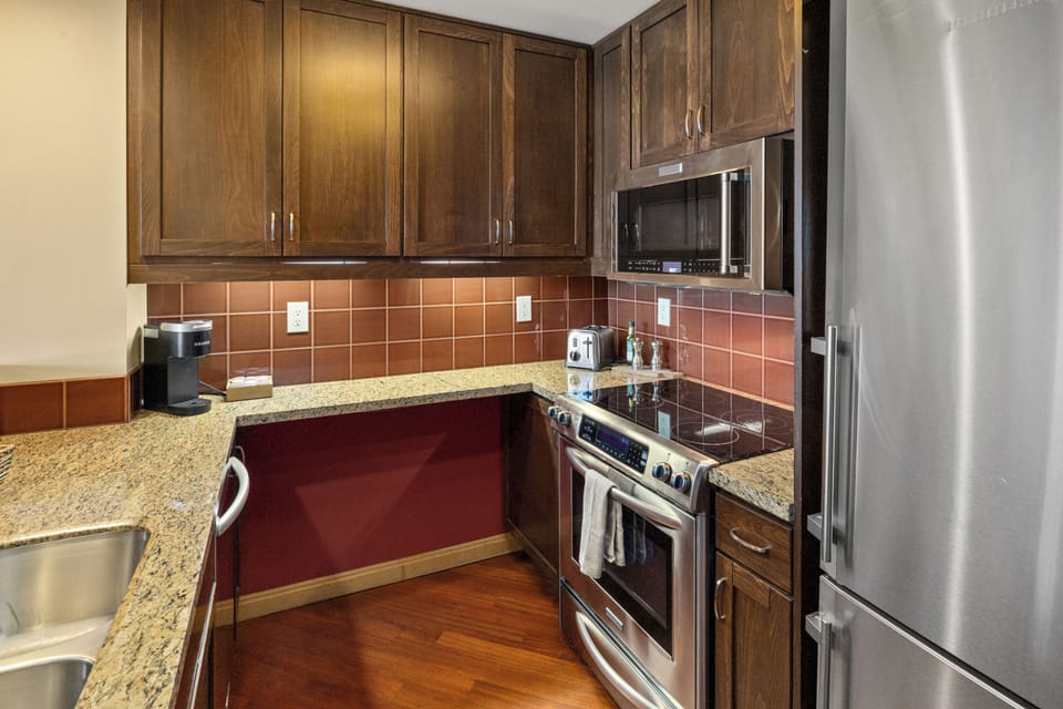 Stylish granite kitchen with stainless appliances and warm wood finishes