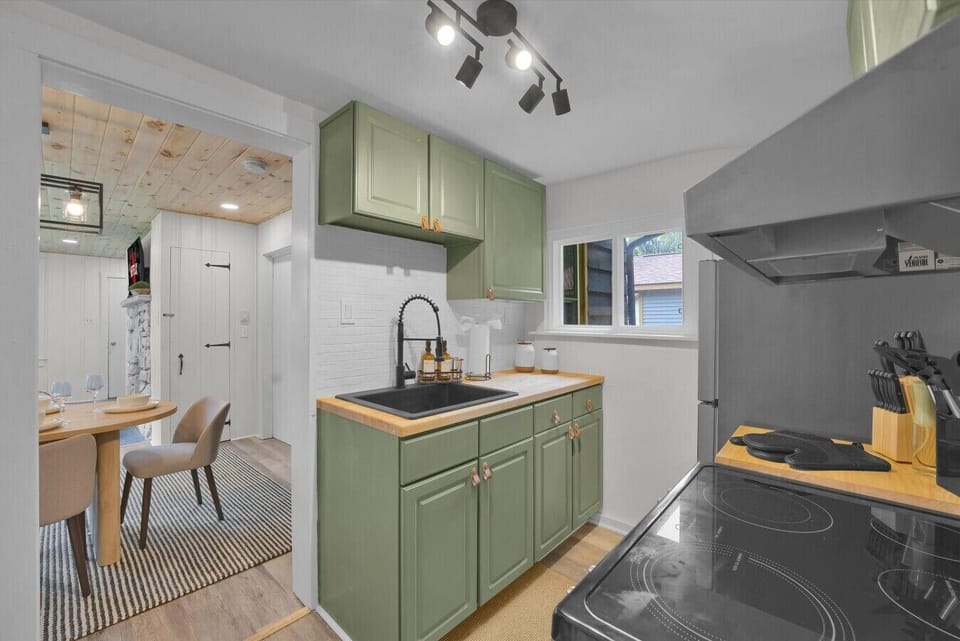 Gather around the table after preparing your favorite meals in the charming sage-green kitchen.