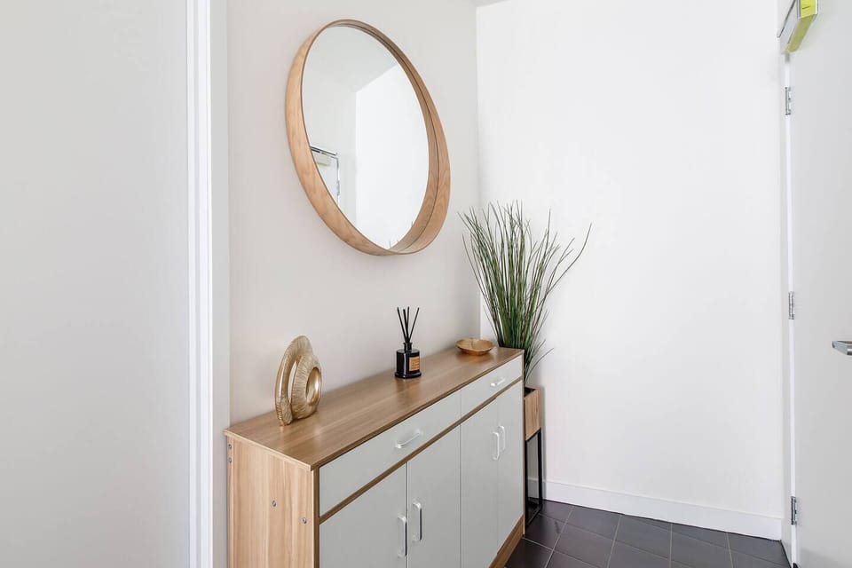 Step into a welcoming entryway featuring modern decor, a sleek console, and a round mirror that sets the tone for a warm, contemporary stay.