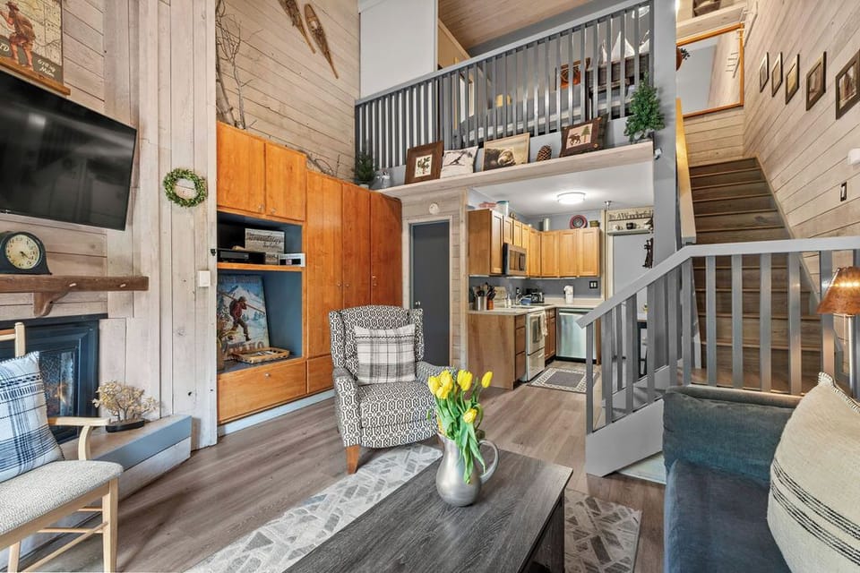 Cozy loft-style cabin with fireplace, open kitchen, and soaring wood ceilings