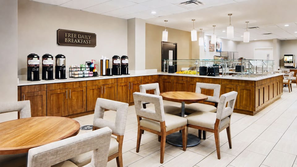 Complimentary breakfast display with coffee machines and a selection of pastries.