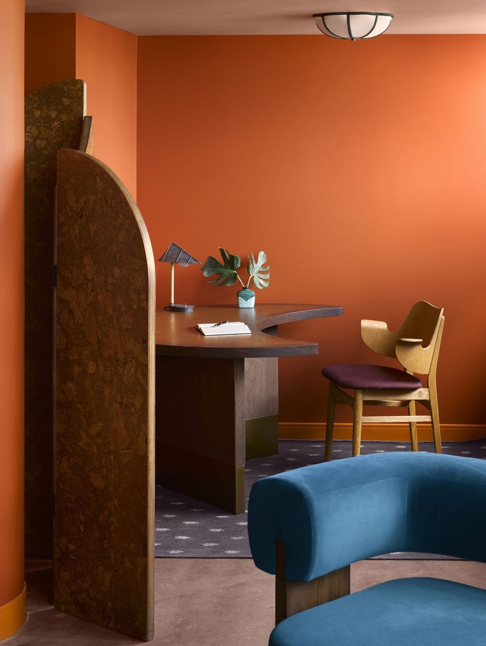 Dedicated workspace with a wood-topped desk and wall-mounted shelving in a bright, art-filled corner of the suite