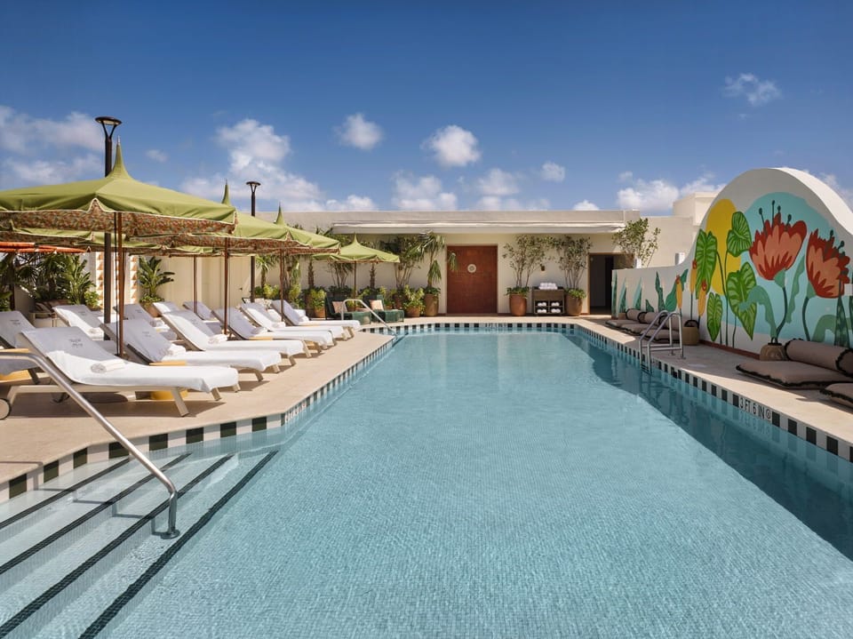 Dive into refreshing waters at the rooftop pool, framed by lush landscaping and colorful murals