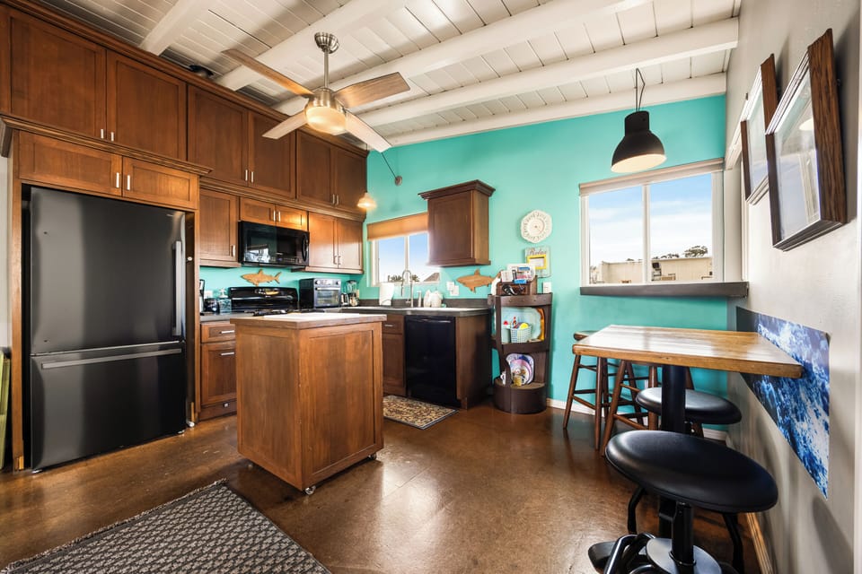 Stunning white exposed-beam ceilings elevate the space, featuring a kitchen island for extra prep and storage.