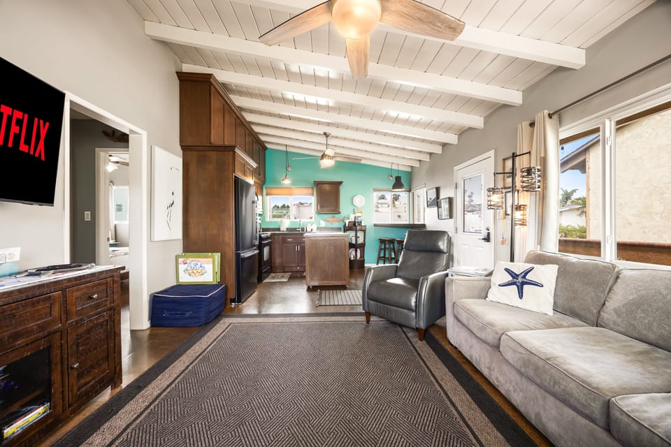 Soaring white exposed-beam vaulted ceilings connect the living room seamlessly to the kitchen and dining areas.