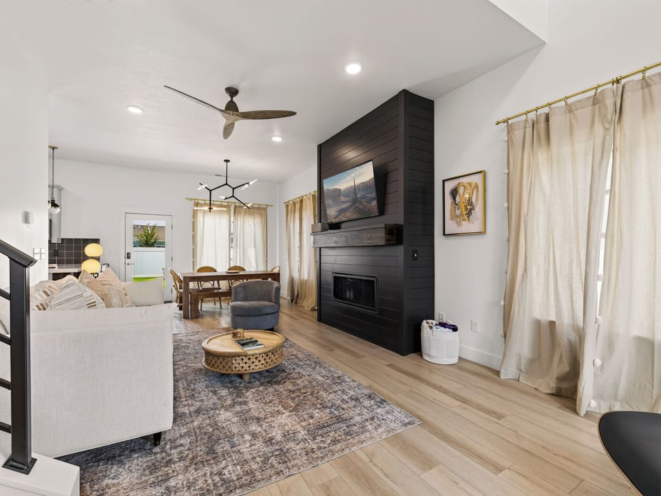 A bright and spacious gathering space with high ceilings and abundant natural light. Modern furnishings and contemporary design create a welcoming atmosphere perfect for entertaining or relaxing as a family. The open floor plan seamlessly connects to dining and kitchen areas, making this the heart of the home ideal for both daily living and hosting guests.