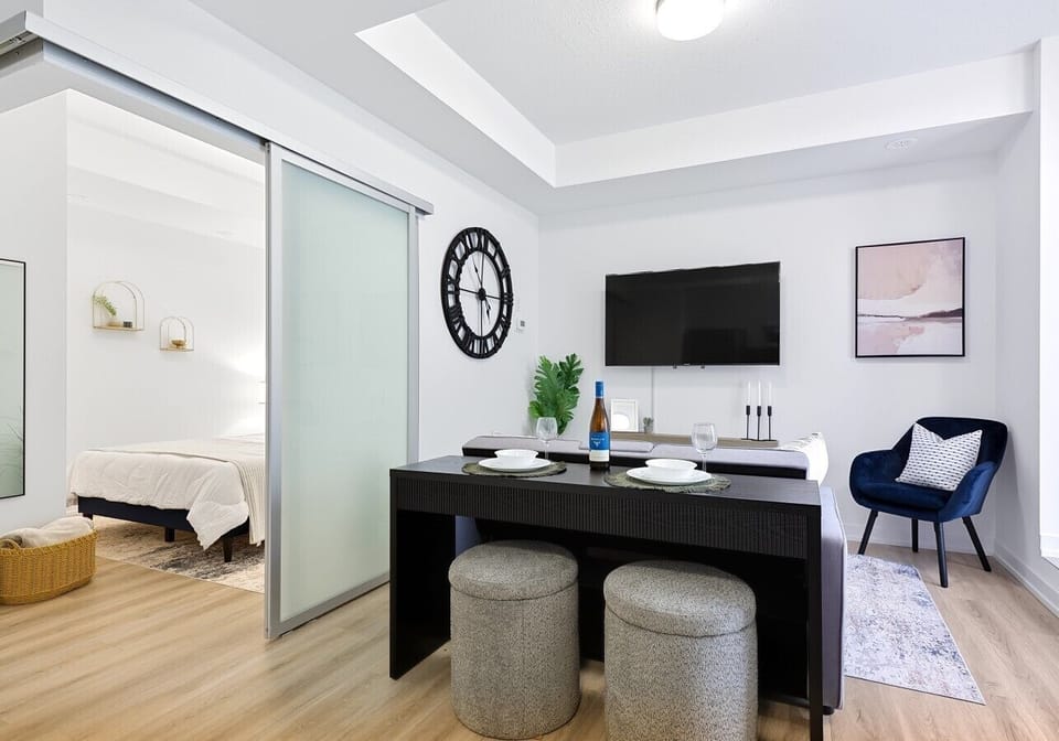 Relax in the bright, open-concept living space designed for both comfort and functionality. Floor-to-ceiling patio doors fill the suite with natural light, while the comfortable seating area and Smart TV make it easy to unwind after a busy day. The dining