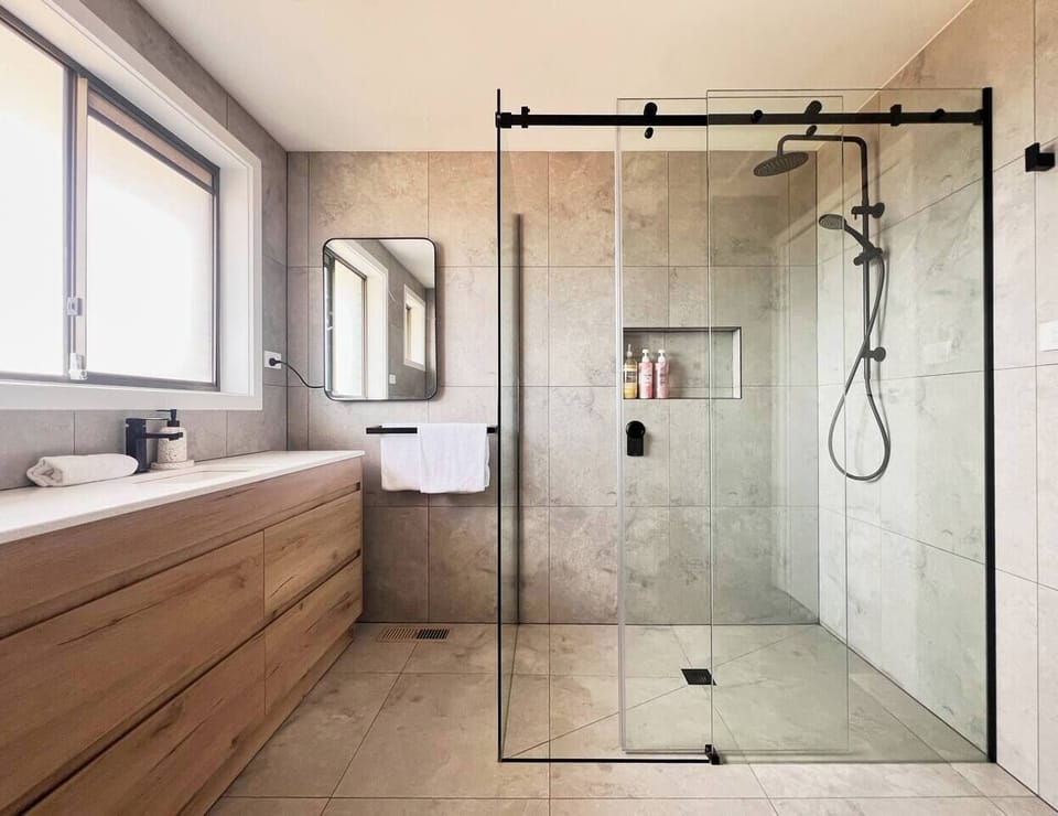 Refresh in the sleek and modern bathroom with a spacious walk-in shower and spacious vanity.