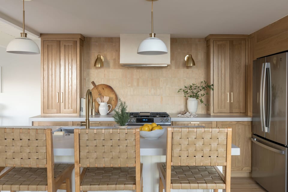Modern kitchen island with gas cooktop and woven barstools.