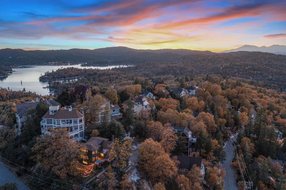 Aerial drone shot of the surrounding forest canopy and sunset horizon.