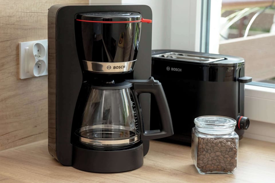 A close-up of a coffee maker and electric kettle placed neatly on the kitchen counter, ready for preparing hot drinks at any time.
