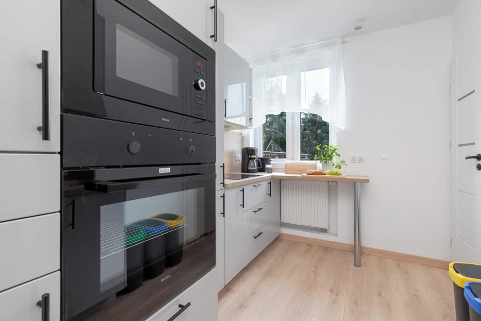 A modern kitchen with built-in appliances, dark oven units, and white cabinetry. The functional layout offers everything needed for preparing meals.