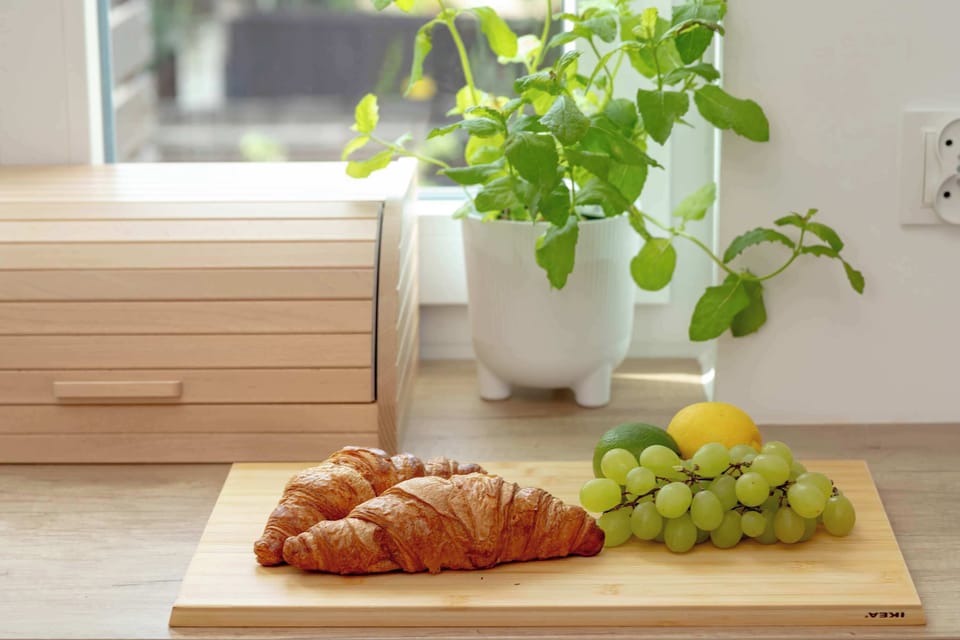 A close-up of fresh pastries, grapes, and a potted herb placed on the wooden countertop. Decorative touches add warmth and character to the kitchen.