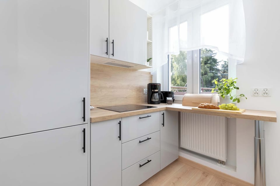A bright kitchen with white cabinets, wooden countertops, and a large window above the work surface. Natural light makes the cooking area feel fresh and inviting.