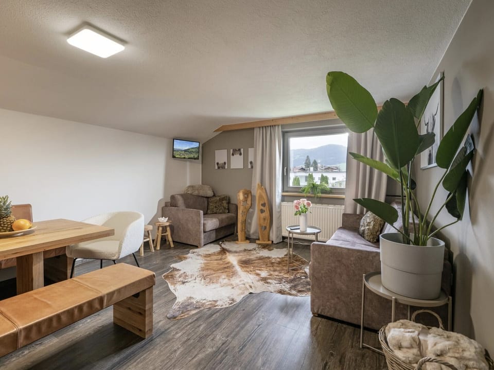 Westendorf vacation rental with living room, sofa, dining area and balcony, a practical base for families near SkiWelt and Alpine trails.