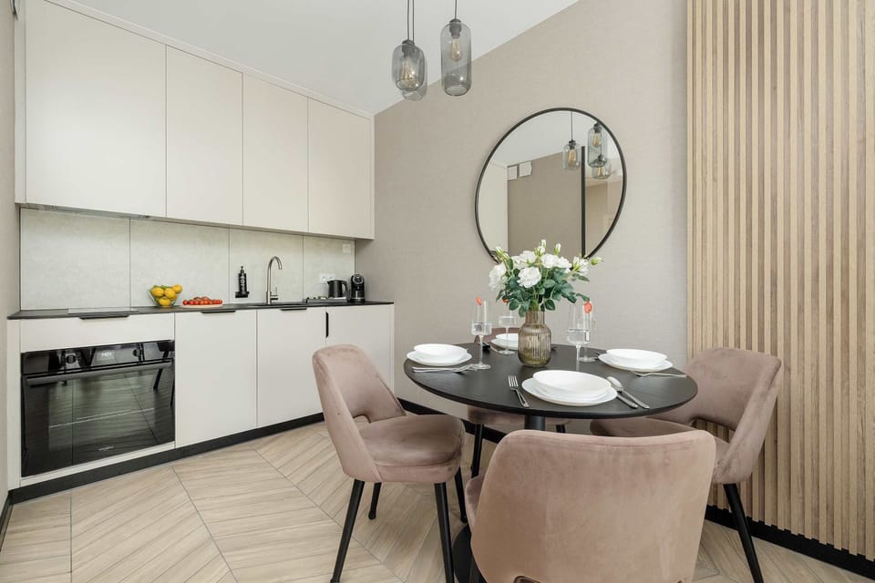 Modern kitchenette with white cabinets, round dining table and comfortable upholstered chairs.