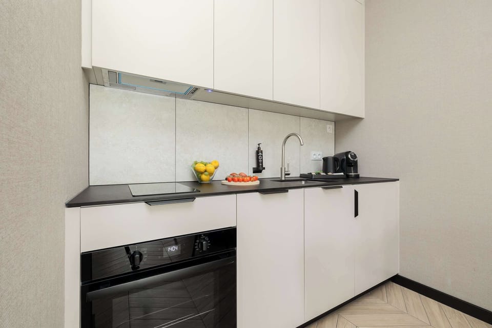 Modern kitchenette with white cabinets, round dining table and comfortable upholstered chairs.