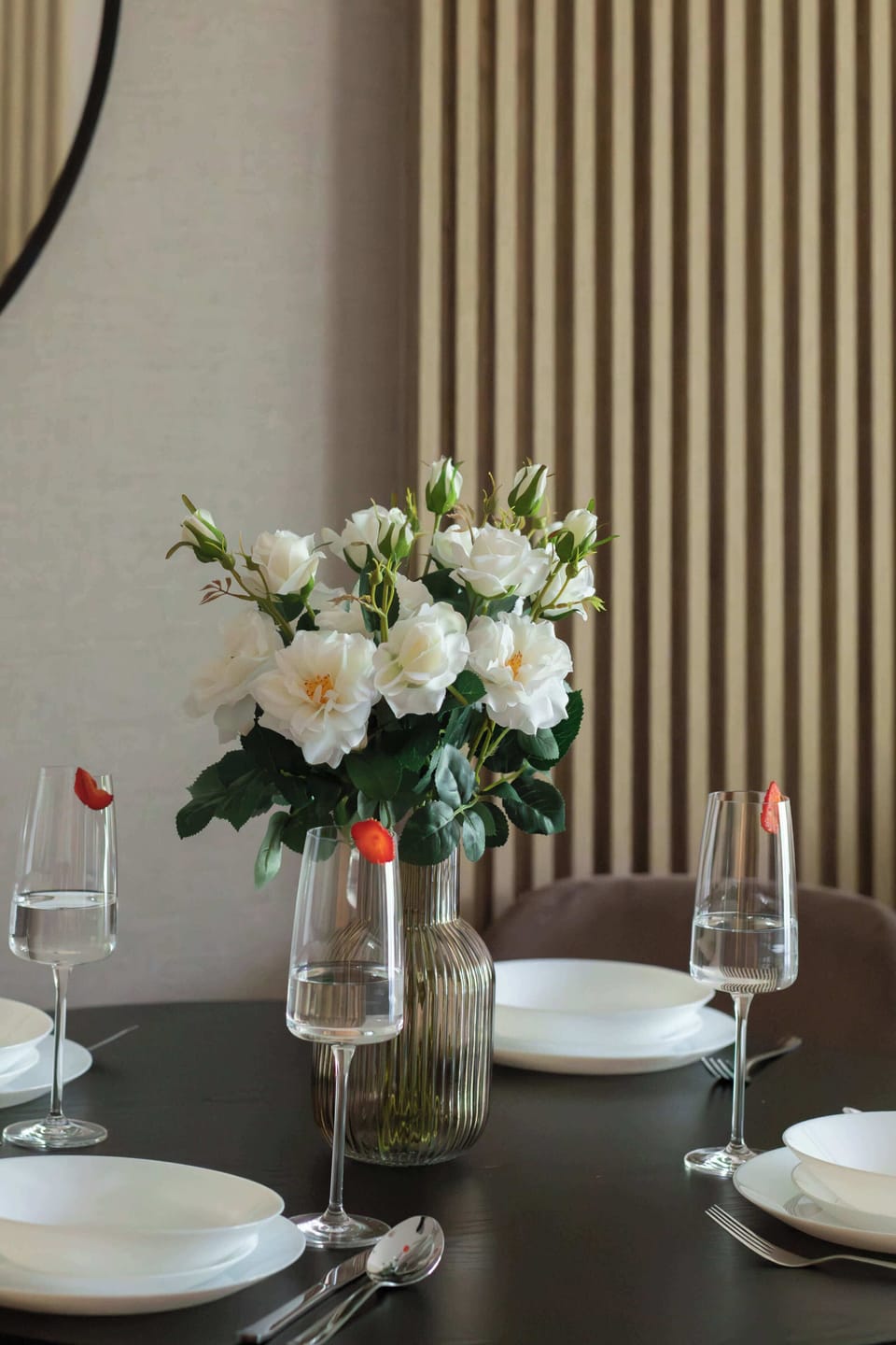 Close-up of living room dining area with decorative flowers, elegant wall paneling and modern furnishings.