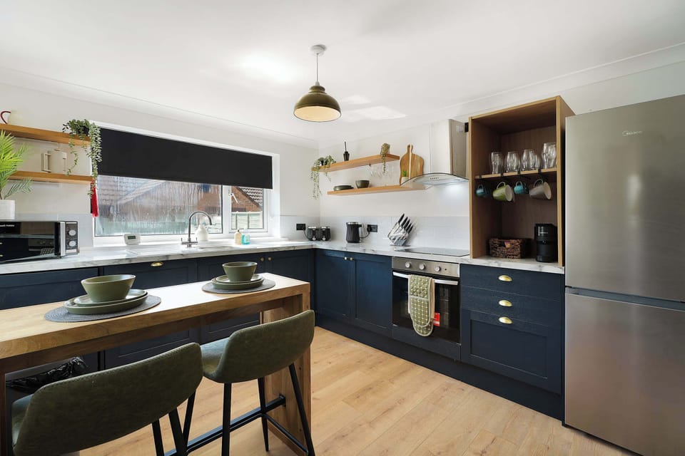 Prepare your favourite meals in the fully equipped kitchen, featuring an oven, hob, microwave, fridge/freezer, washing machine, breakfast table, and a selection of essential cookware.