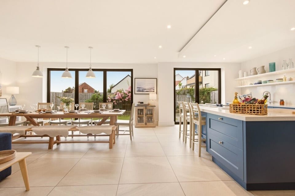 Open-plan kitchen and dining area with blue island and full-width dining table