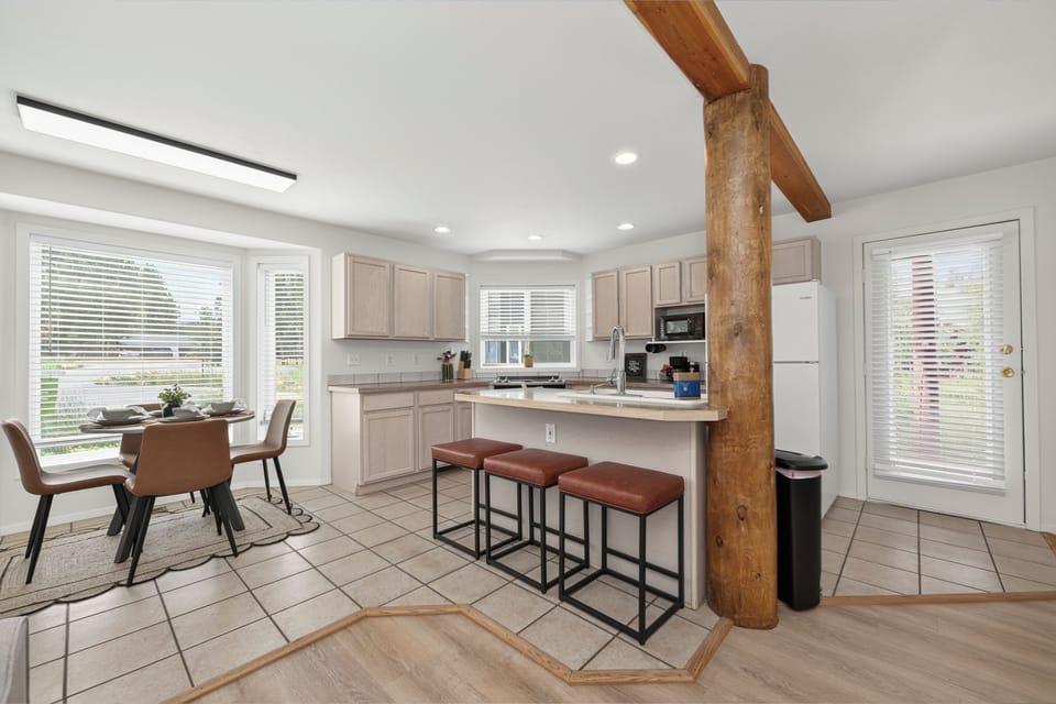 Whip up your favorite meals in this bright, fully equipped kitchen with rustic wooden beams and a breakfast bar perfect for casual dining. Natural light pours in from large windows, creating a warm and welcoming space for your mornings.